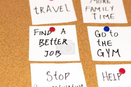 Photo for Close up of white post-it notes with new year's resolutions on a cork board. Texts: Find a better job and Go to the gym - Royalty Free Image