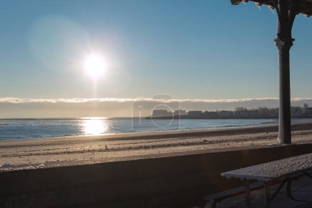 Photo for A beach during a cold winter sunrise seen from a kiosk. Revere, Massachusetts. - Royalty Free Image