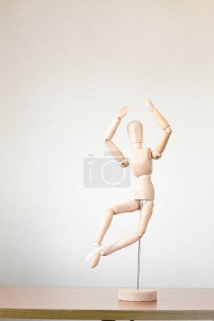 Foto de Un maniquí de dibujo saltando en celebración sobre una mesa con las manos levantadas - Imagen libre de derechos
