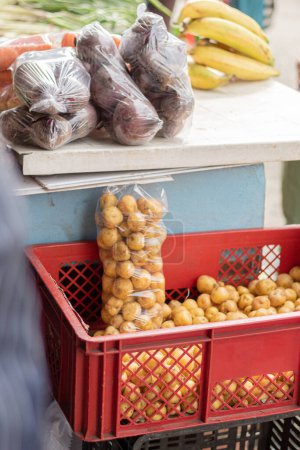 Téléchargez les photos : Aliments biologiques au marché fermier. Petites pommes de terre jaunes dans un panier en plastique. Papa Criolla de Colombie. Concept d'alimentation biologique - en image libre de droit