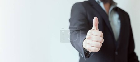 Foto de Un hombre de negocios vestido con un traje sin corbata con los pulgares hacia arriba sobre un fondo blanco-gris. Señal de aprobación y satisfacción. Banner web, Copiar espacio. - Imagen libre de derechos