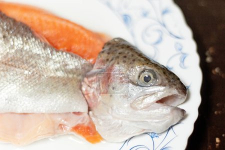 Téléchargez les photos : Gros plan d'une truite crue. Un poisson fileté sur une assiette blanche. - en image libre de droit