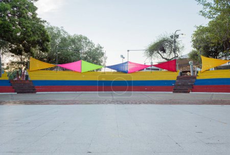 Foto de Melgar, Colombia - 6 de abril de 2024. Personas tomando un autobús Cafachiva o simplemente Chiva un colorido autobús rural en frente de la entrada de Cafalandia, un parque familiar ubicado en el complejo Cafam, Melgar en Tolima Colombia. - Imagen libre de derechos