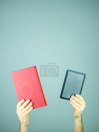 Photo for Two hand holding a red cover paper book and an electronic book - Royalty Free Image