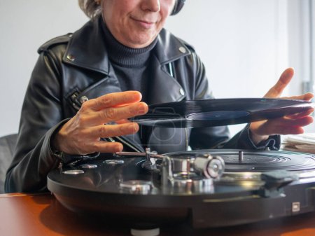 Eine unkenntliche Dame hält eine Schallplatte bereit, um sie auf ihrem Plattenspieler abzuspielen