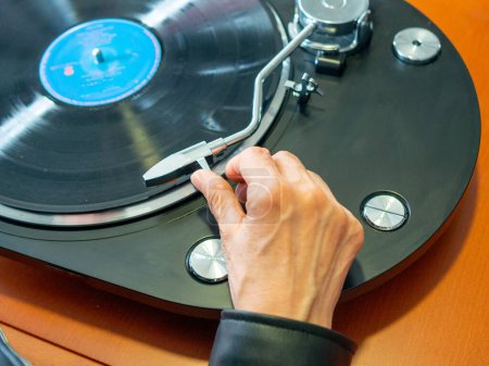 Lady Hand hält den Tonarm ihres Plattenspielers bereit, um eine Schallplatte abzuspielen
