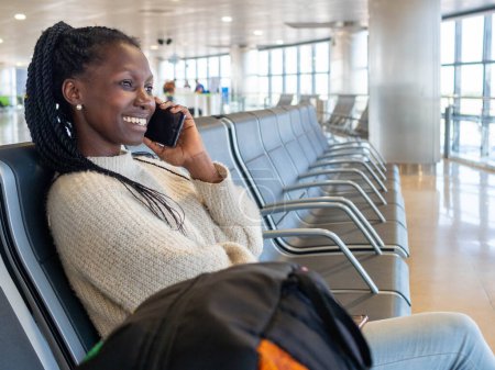 A young woman using her phone while waiting for her flight in the airport lounge
