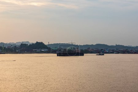 Der Blick auf den Fluss Mahakam bei Sonnenuntergang ist mit Segelschiffen und Gebäuden rund um den Fluss geschmückt.