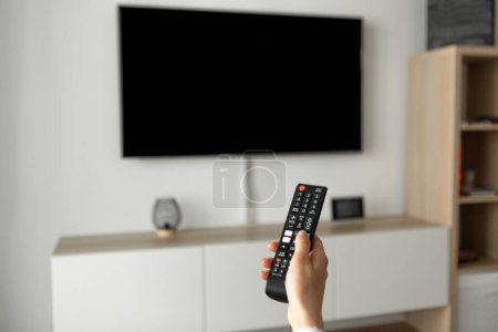 Foto de Un hombre ve la televisión y usa el mando a distancia. Foto de alta calidad - Imagen libre de derechos