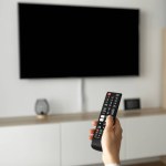A man watches TV and uses the remote control. High quality photo