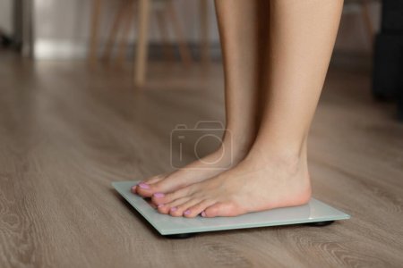 Photo for A woman measures her weight with a scale on a wooden floor. High quality photo - Royalty Free Image