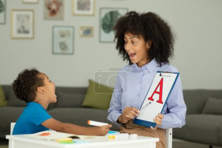 Photo for A little boy learns the letter A with a private English tutor during a lesson at home. High quality photo - Royalty Free Image