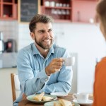 Happy young european couple talking over a cup of coffee at cafe, man and woman sitting at coffee shop having a conversation while having coffee