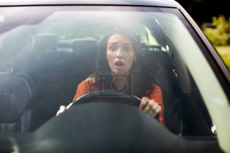 Retrato de vista frontal de una mujer asustada conduciendo un auto antes de un accidente y mirando con expresión facial asustada