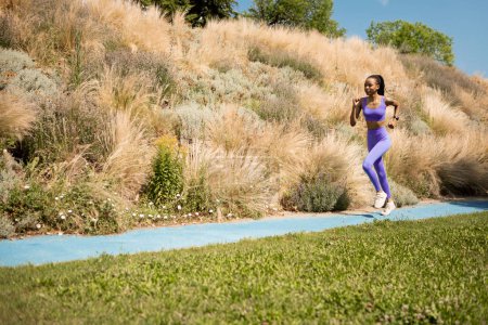 Young athletic woman in sportswear running in nature in the morning, enjoying workout outdoors, full length, free space