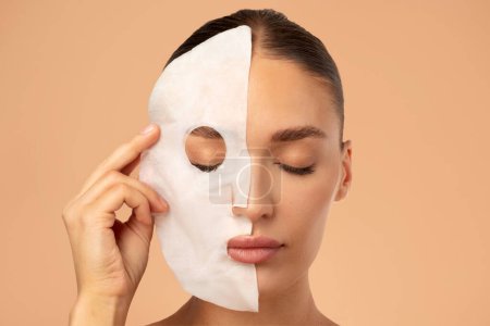 Beauty routines. Closeup of young lady removing textile sheet mask from facial skin, enjoying result of skin treatments, beige background