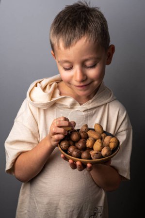Photo for Boy holding a bowl with pecan and macadamia nuts. Healthy food and snack. - Royalty Free Image