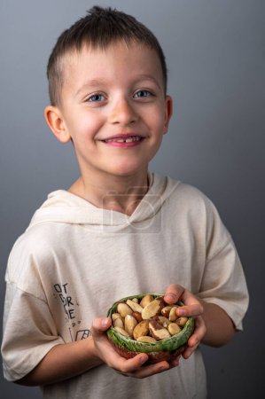 Photo for Boy holding a small bowl with brasil nuts. Healthy food and snack. - Royalty Free Image