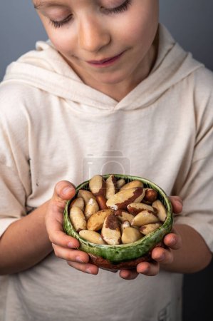 Photo for Children hands holding a small bowl with brasil nuts. Healthy food and snack. - Royalty Free Image