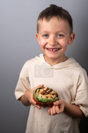 Foto de Niño sosteniendo un tazón pequeño con nueces brasileñas. Comida y merienda saludables. - Imagen libre de derechos