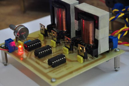 Foto de Un circuito electrónico de un amplificador de tensión y corriente. que consiste en un transformador, IC, condensador, potenciómetro, transistor, cable de toma, y led - Imagen libre de derechos