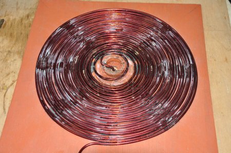 Foto de Herida de alambre de cobre sin blindaje para formar un disco. se hace para conseguir una inducción eléctrica grande - Imagen libre de derechos