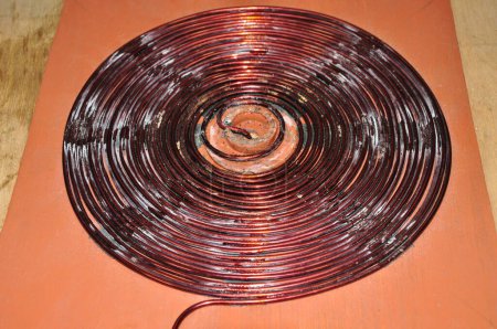 Foto de Herida de alambre de cobre sin blindaje para formar un disco. se hace para conseguir una inducción eléctrica grande - Imagen libre de derechos