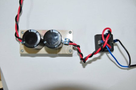Foto de Condensador electrolítico y puente de diodo que son parte del circuito del convertidor de voltaje, están conectados por cables azules y rojos. el circuito convierte el voltaje de CA a CC - Imagen libre de derechos