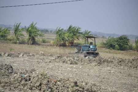 Photo for Dry land being leveled by a small bulldozer. this is usually done in rice fields that are about to be converted into settlements - Royalty Free Image