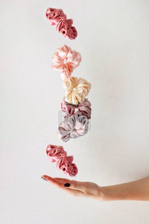 levitation of Colorful silk Scrunchies on woman hand isolated white. Hairdressing tools and accessories. Hair Scrunchies, Elastic HairBands, flying or falling Scrunchie Hairband for girl. copy space