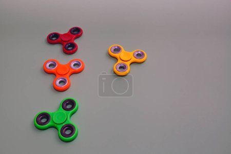 Foto de Juguete spinner escupir sobre fondo violeta. cuatro juguetes de mano coloridos - juego muy popular - Imagen libre de derechos