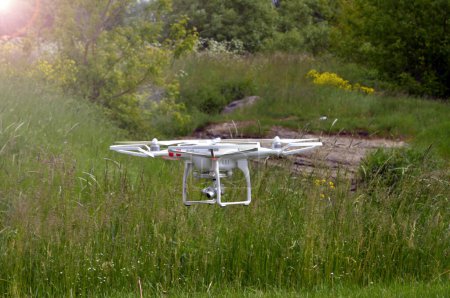 Photo for Drone with professional digital camera takes picture. copter flying or Hexacopter at summer day behind green grass - Royalty Free Image