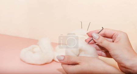 Téléchargez les photos : Aiguille en laine feutrée bannière et écheveau de laine sur table rose. femme main tenant kit de feutrage aiguille. pose plate, artisanat d'en haut - en image libre de droit