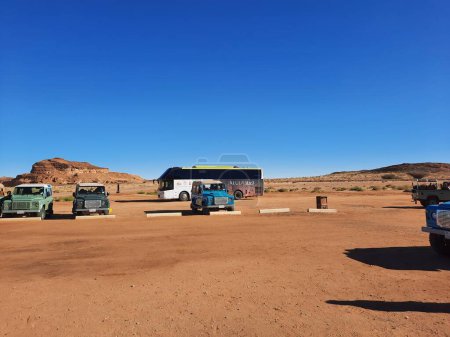 Foto de Los autobuses están estacionados en diferentes lugares del desierto para llevar a los turistas a diferentes lugares durante el día en Al-Ula, Arabia Saudita. - Imagen libre de derechos