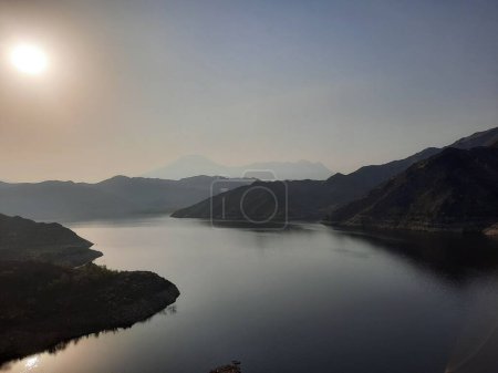 Téléchargez les photos : Une belle vue de jour sur le barrage de Wadi Qanuna à Al Bahah, en Arabie Saoudite. L'eau du barrage et les collines environnantes présentent une belle scène au soleil. - en image libre de droit