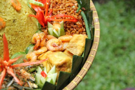Foto de Guarniciones de Nasi Tumpeng, como camarones fritos, tempeh seco, tofu frito, verduras y pepino - Imagen libre de derechos