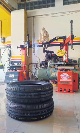 Foto de Bandung, Indonesia - 30 de mayo de 2023; un par de neumáticos nuevos y no equipados para automóviles se mantienen en el suelo. En el taller de spooring y equilibrio - Imagen libre de derechos