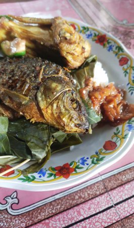Téléchargez les photos : Une assiette de nourriture indonésienne simple, poisson frit, poulet frit, sauce chili et légumes frais - en image libre de droit