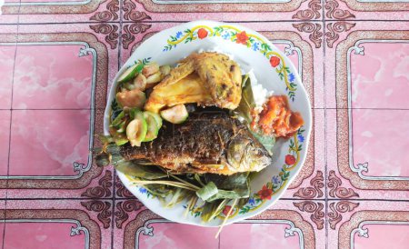Téléchargez les photos : Une assiette de nourriture indonésienne simple, poisson frit, poulet frit, sauce chili et légumes frais - en image libre de droit
