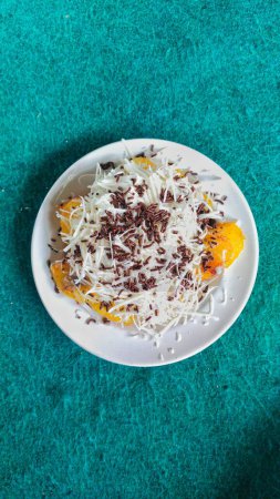 a plate of Indonesia's favorite snack food, "Pisang Keju", pieces of fried banana sprinkled with a generous topping of grated cheese, a drizzle of sweetened condensed milk and chocolate sprinkles
