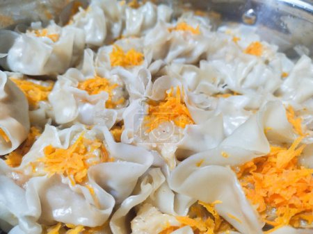 Fish stuffed dumplings topped with thinly sliced carrots, cooked after a few minutes of steaming