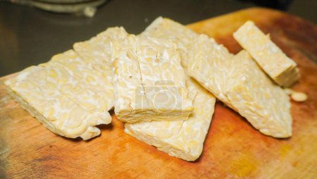 pile raw tempeh pieces on a wooden cutting board