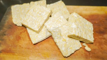 pile raw tempeh pieces on a wooden cutting board