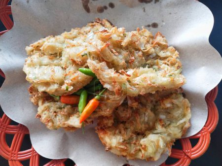 a plate of Bala-bala is served with some small chili. Bala-bala is made from a mixture of wheat flour dough with several types of vegetables such as carrots and cabbage and then fried