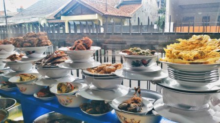 Varios menús en los puestos de arroz Padang se muestran apilados detrás del vidrio. Estos incluyen rendang de carne de res, pollo a la parrilla, migas de camarones, tortilla, etc.