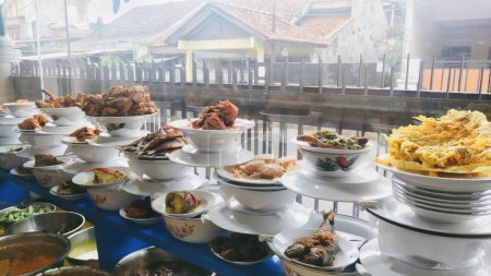 Varios menús en los puestos de arroz Padang se muestran apilados detrás del vidrio. Estos incluyen rendang de carne de res, pollo a la parrilla, migas de camarones, tortilla, etc.