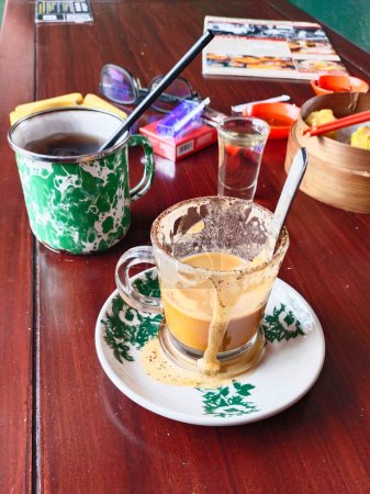mesa de madera después del almuerzo en un restaurante chino lleno de vasos de té de café y leche, cigarrillos, salsa de chile y vapores dim sum
