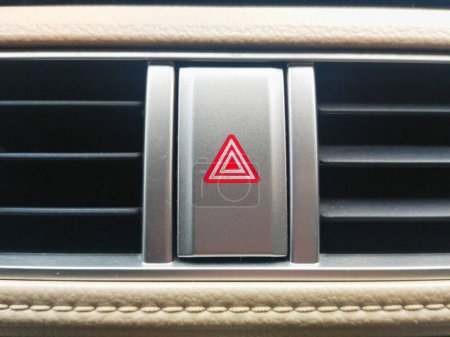 gros plan du bouton lumineux Hazard en forme de triangle rouge, à l'intérieur d'une voiture