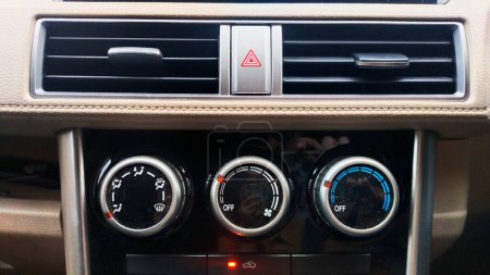 features on the front of the car cabin such as the Hazard light button between the AC ventilation grilles, and the AC setting control wheels