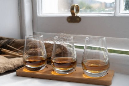 Foto de Flight of single malt and blended scotch whisky served on old wooden window sill in Scottisch house in Edinburgh, Scotland, UK, dram of whiskey - Imagen libre de derechos